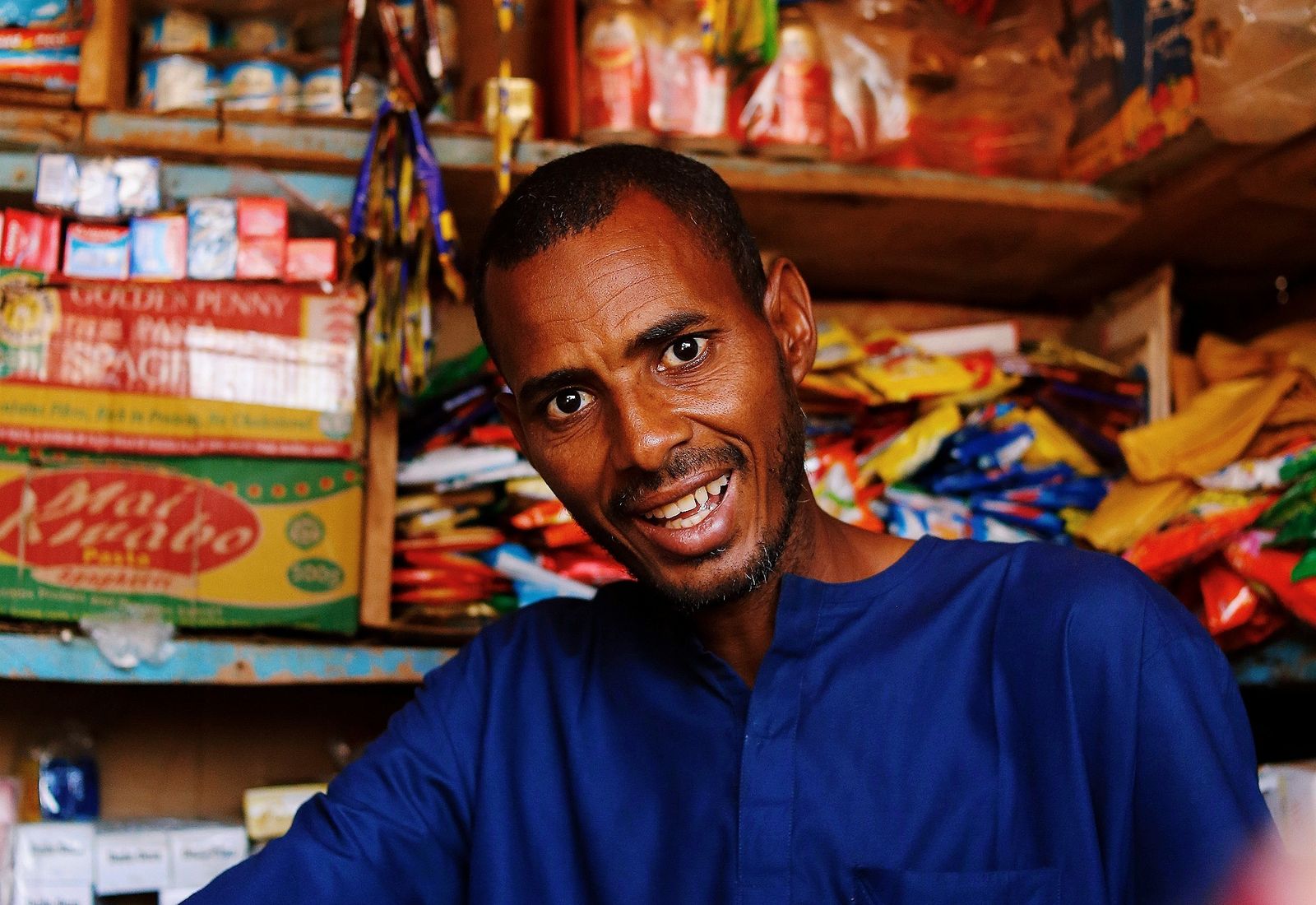 A shopkeeper behind the counter of his well stocked shop